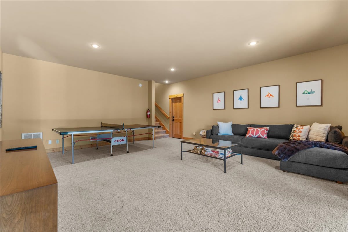 Spacious game room in a Truckee vacation rental, featuring a ping pong table, cozy sofa, and wall art.