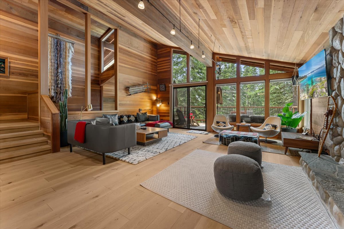 Spacious living room in a Carnelian Bay vacation rental with wooden interiors, modern furniture, and large windows.