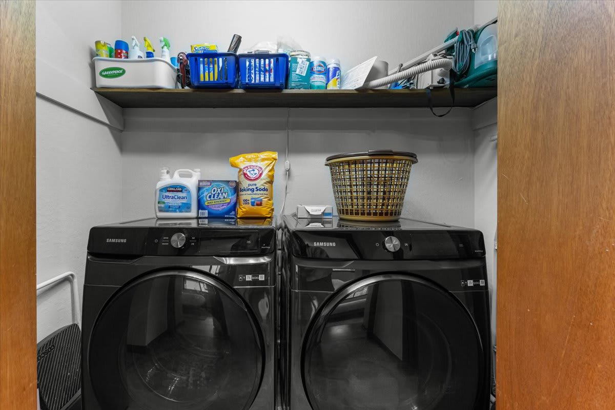 Laundry room in Carnelian Bay vacation rental with washer, dryer, cleaning supplies, and laundry basket.