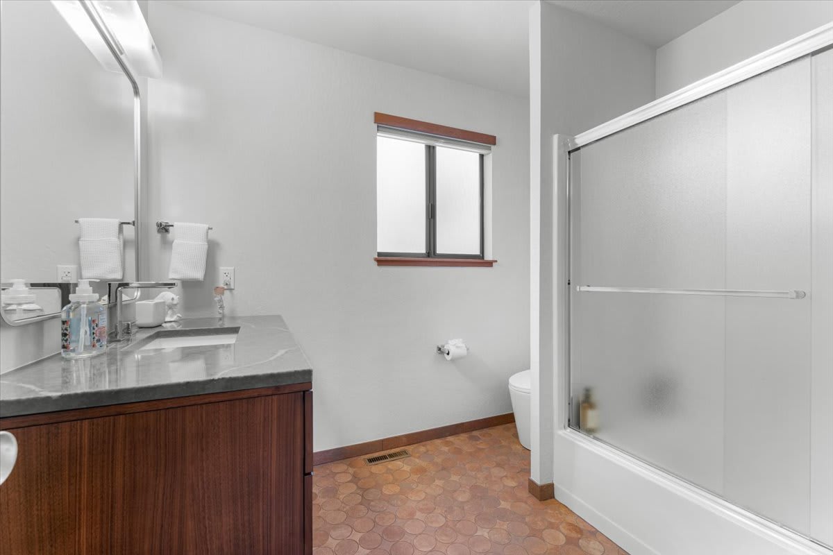 Modern bathroom with shower and wooden vanity in a Carnelian Bay vacation rental.