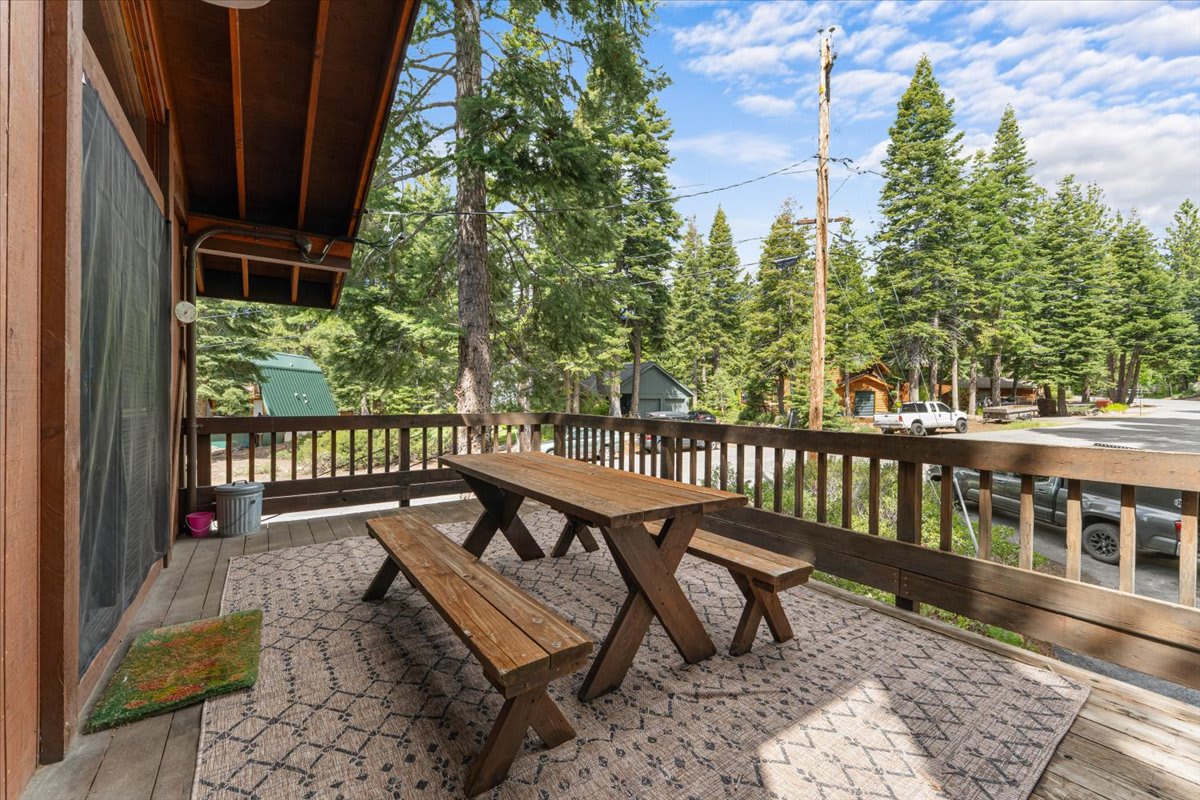 Wooden deck with picnic table overlooking trees and road at a vacation rental in Carnelian Bay.
