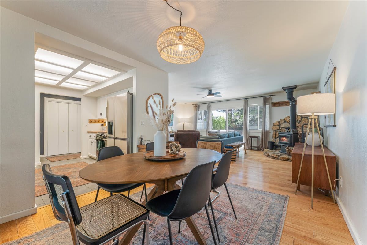 Modern dining area and cozy living room in a Truckee vacation rental, featuring wooden floors and a fireplace.