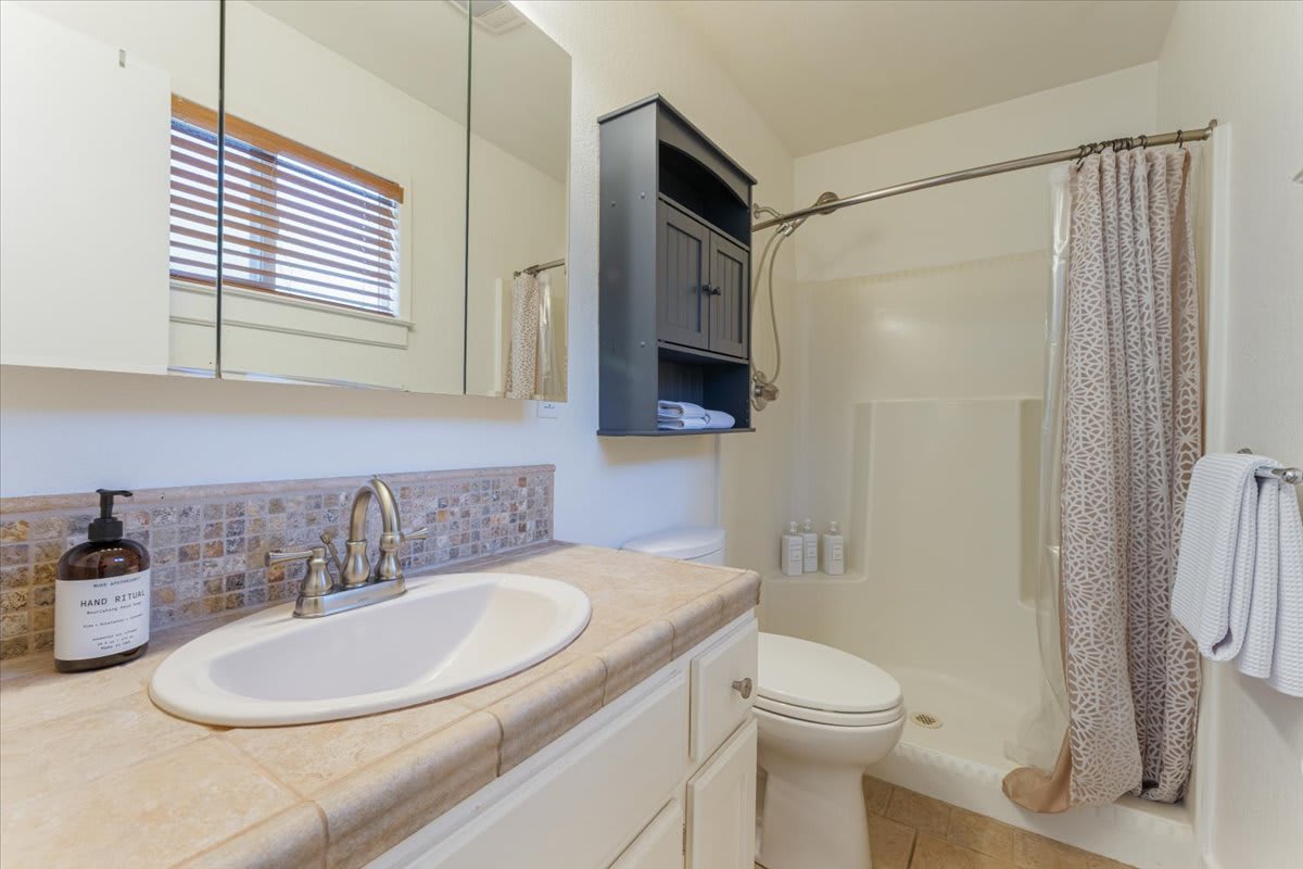 Bathroom in Truckee vacation rental with tiled sink, shower, and shelves.
