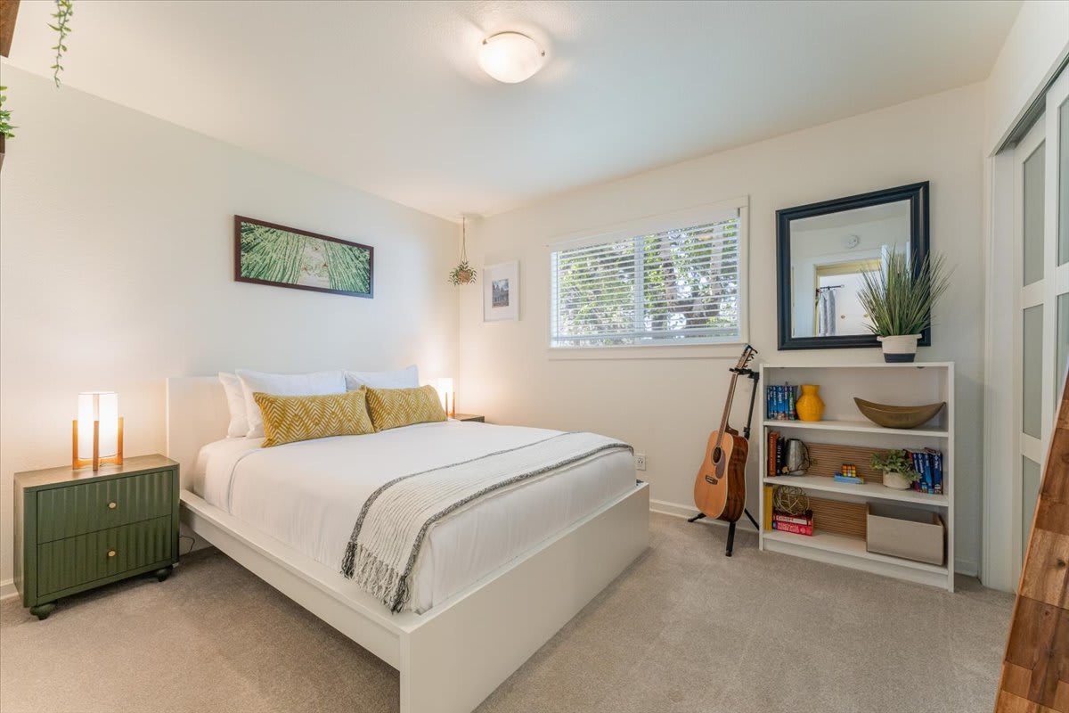 Bedroom in a Truckee vacation rental, featuring a cozy bed, nightstand lamps, a guitar, and bookshelf decor.