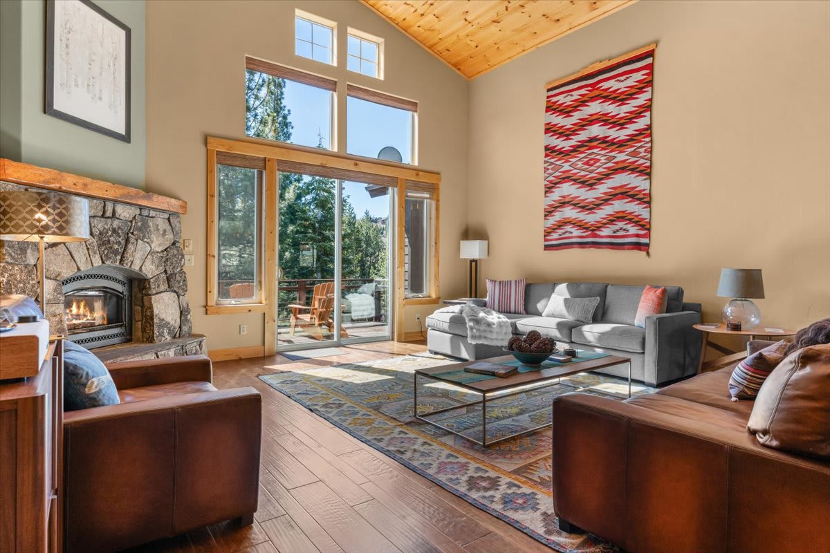 Cozy living room in Truckee vacation rental with fireplace, large windows, and a mix of modern and rustic decor.