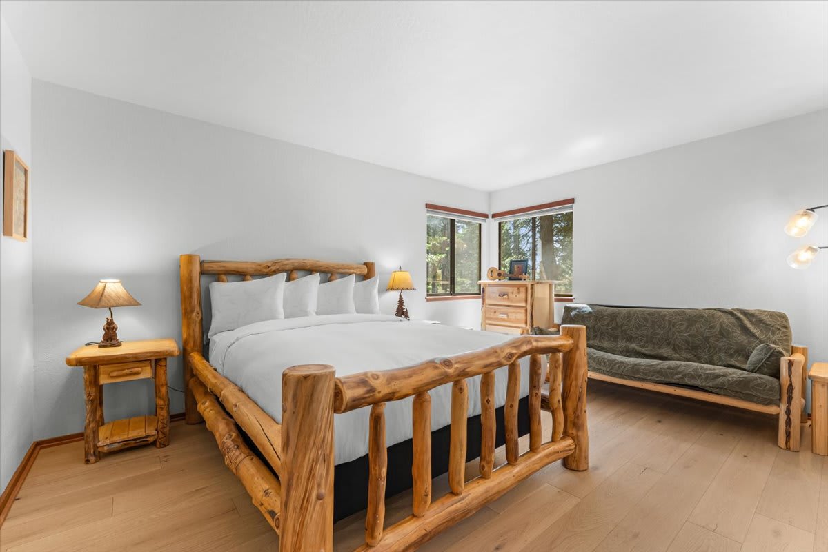 Rustic bedroom in Carnelian Bay vacation rental with log furniture and wooded views through large windows.