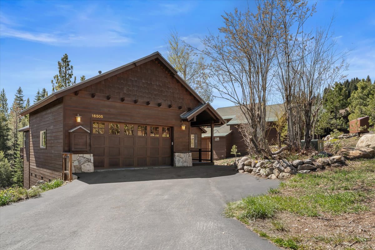 Charming cabin-style vacation rental in Truckee, surrounded by trees and a clear, blue sky.