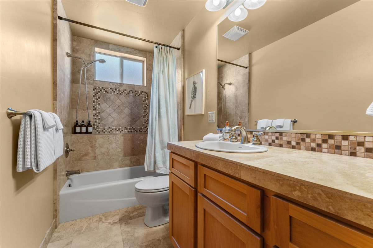 Modern bathroom in a Truckee vacation rental, featuring a tiled shower, wooden cabinets, and a spacious countertop.