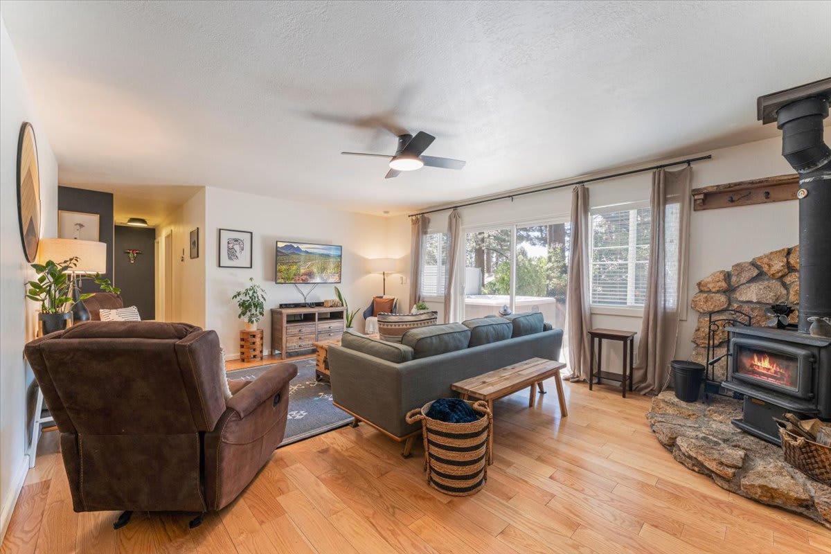 Cozy living room in a Truckee vacation rental with a stone fireplace, modern furniture, and large windows with curtains.