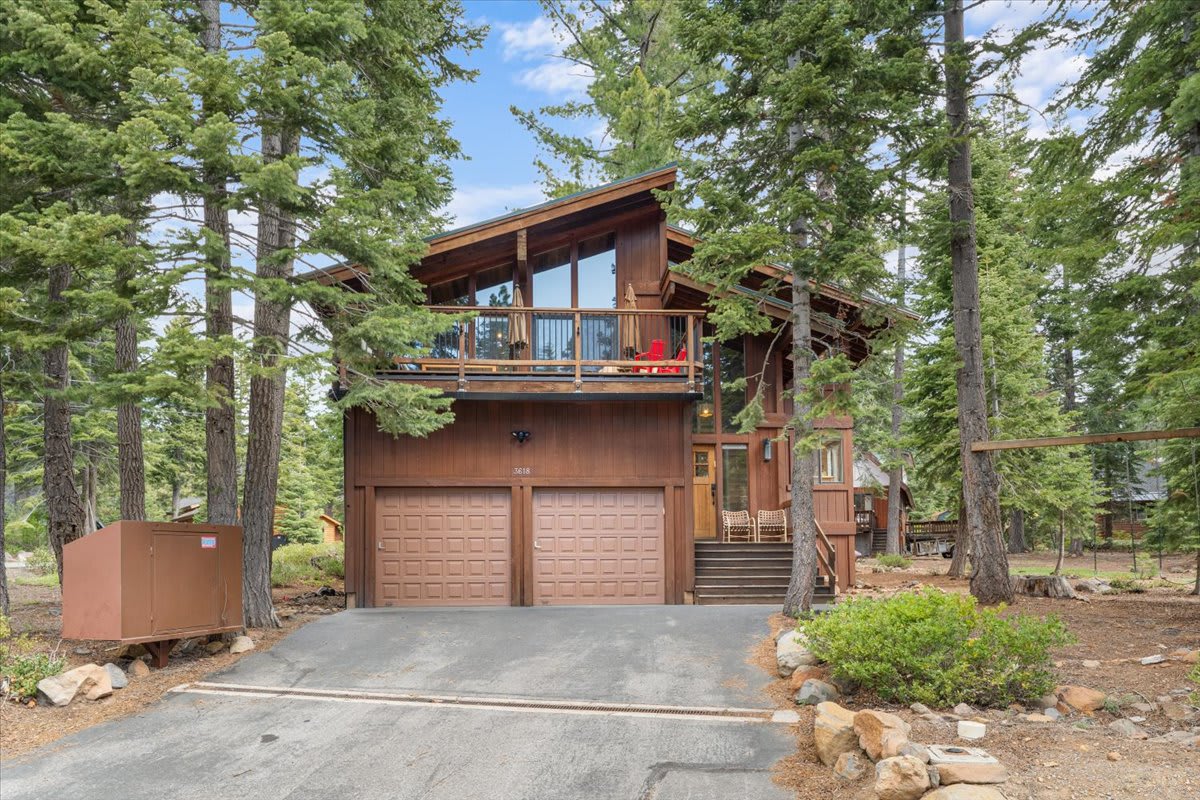 A rustic vacation rental cabin surrounded by trees in Carnelian Bay, featuring large windows and a spacious balcony.