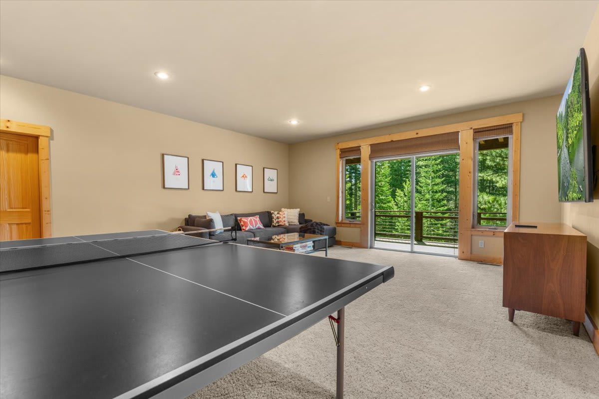 Spacious Truckee vacation rental with a ping pong table, cozy seating, and forest views through large windows.