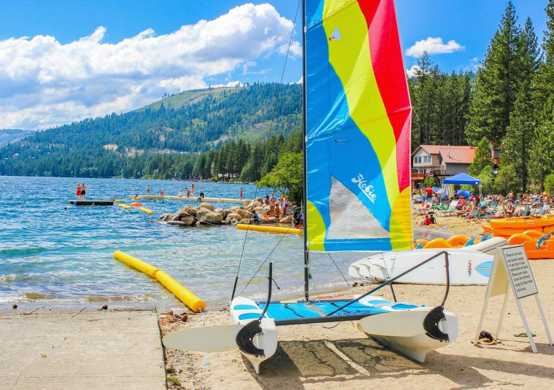 A vibrant sailboat on the sandy shore of a lake in Truckee. Ideal vacation rental spot for summer fun and relaxation.
