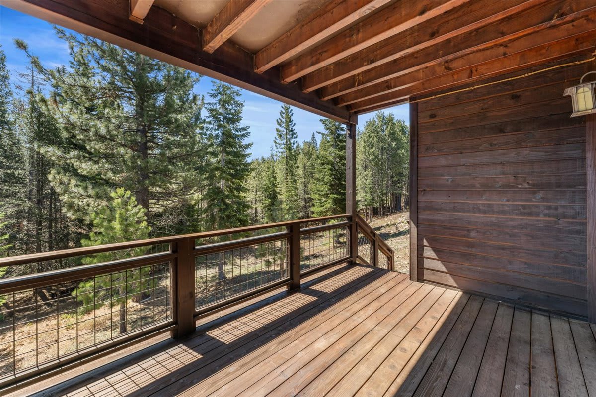 Wooden deck of a Truckee vacation rental, overlooking a scenic forest view with tall trees.
