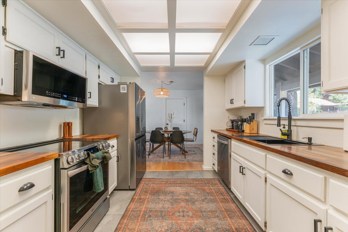 Modern kitchen in a Truckee vacation rental, featuring wood countertops, stainless steel appliances, and dining area.
