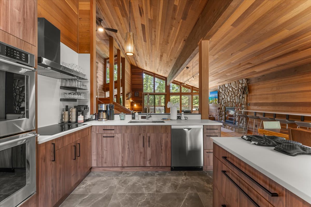 Modern kitchen in Carnelian Bay vacation rental with wood accents, stainless appliances, and stone fireplace view.