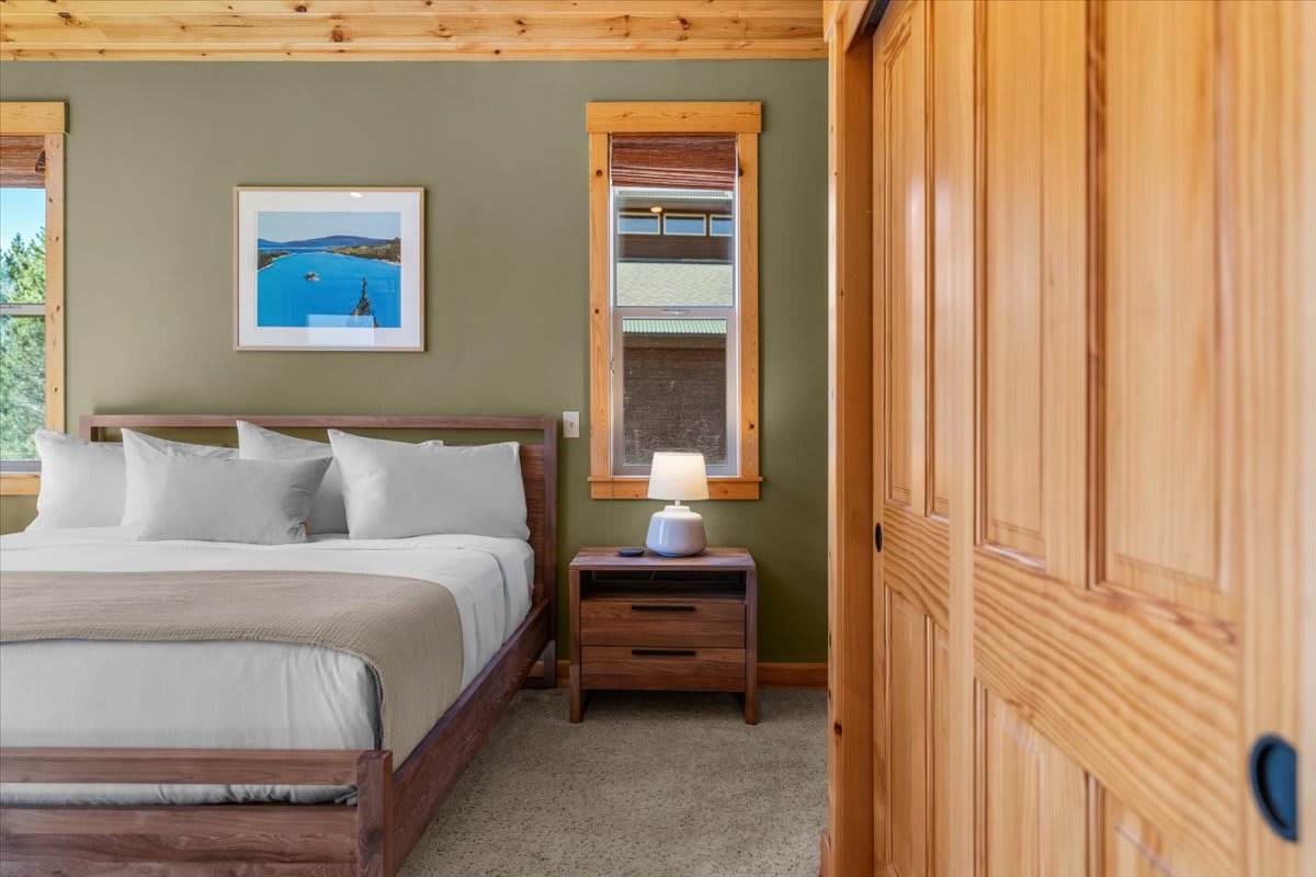 Cozy bedroom in a Truckee vacation rental with a wood finish, framed art, and a bedside lamp.