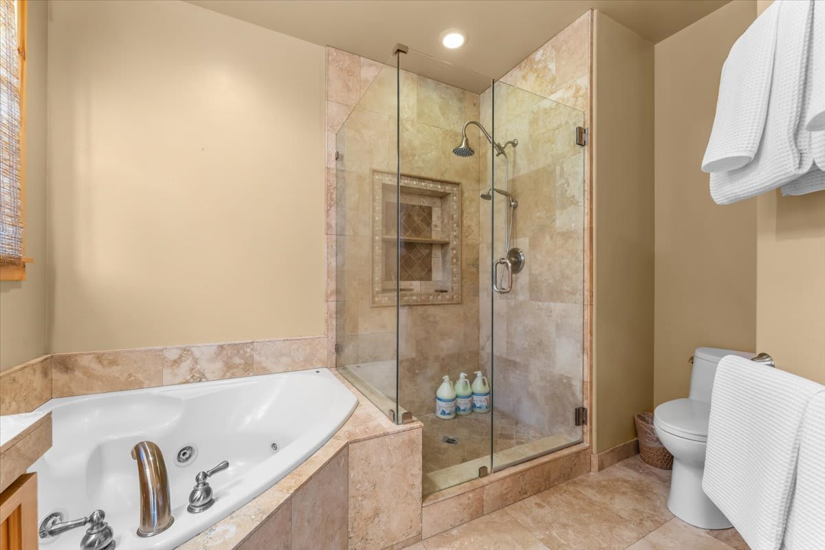 Bathroom in a Truckee vacation rental with a jacuzzi tub, glass shower, and white towels.