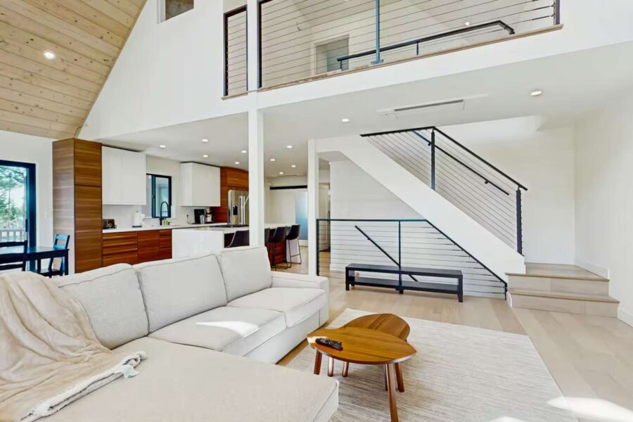 Modern living room and kitchen in a Truckee vacation rental, featuring a plush sofa and sleek wooden accents.