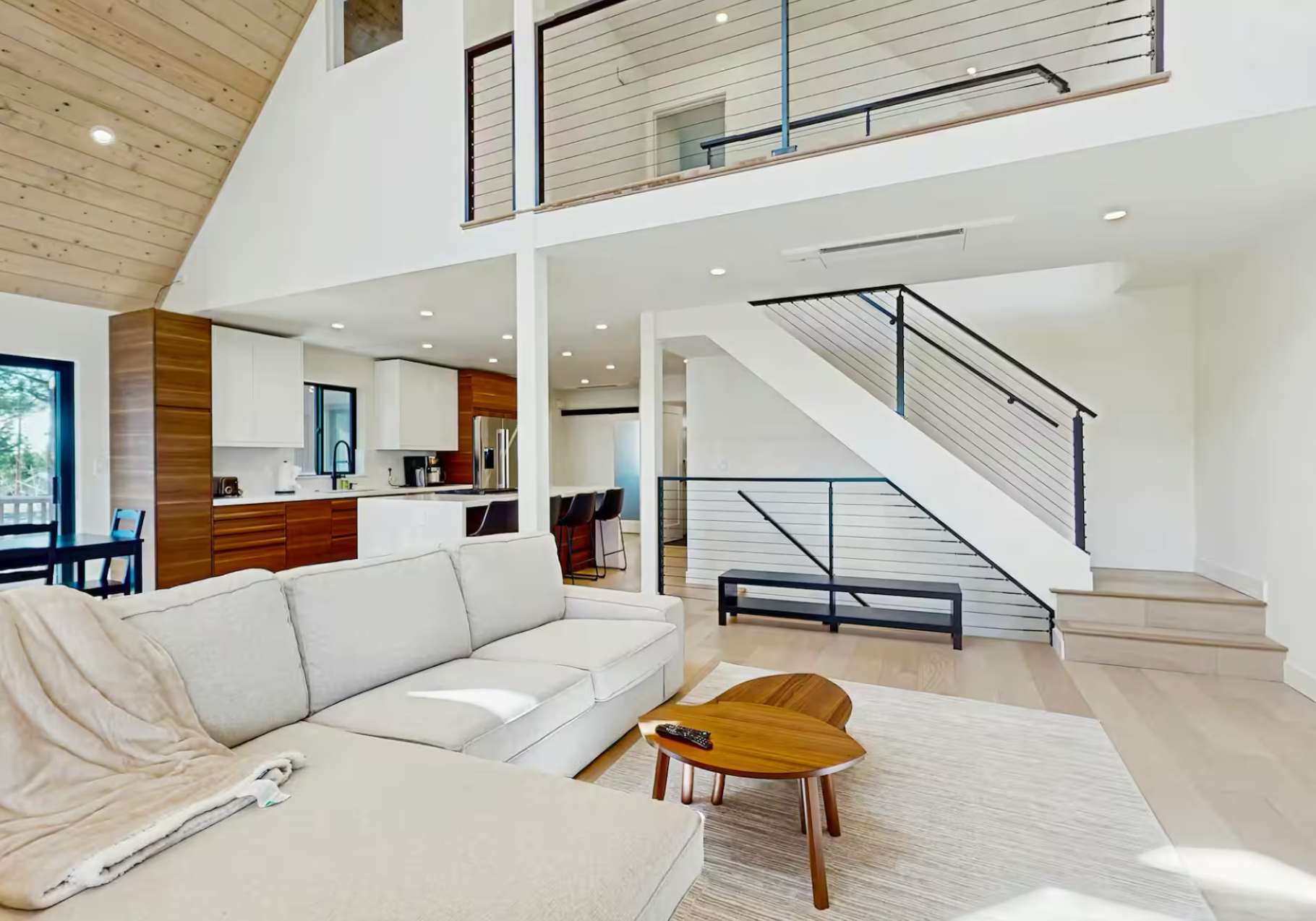Modern living room and kitchen in a Truckee vacation rental, featuring a plush sofa and sleek wooden accents.
