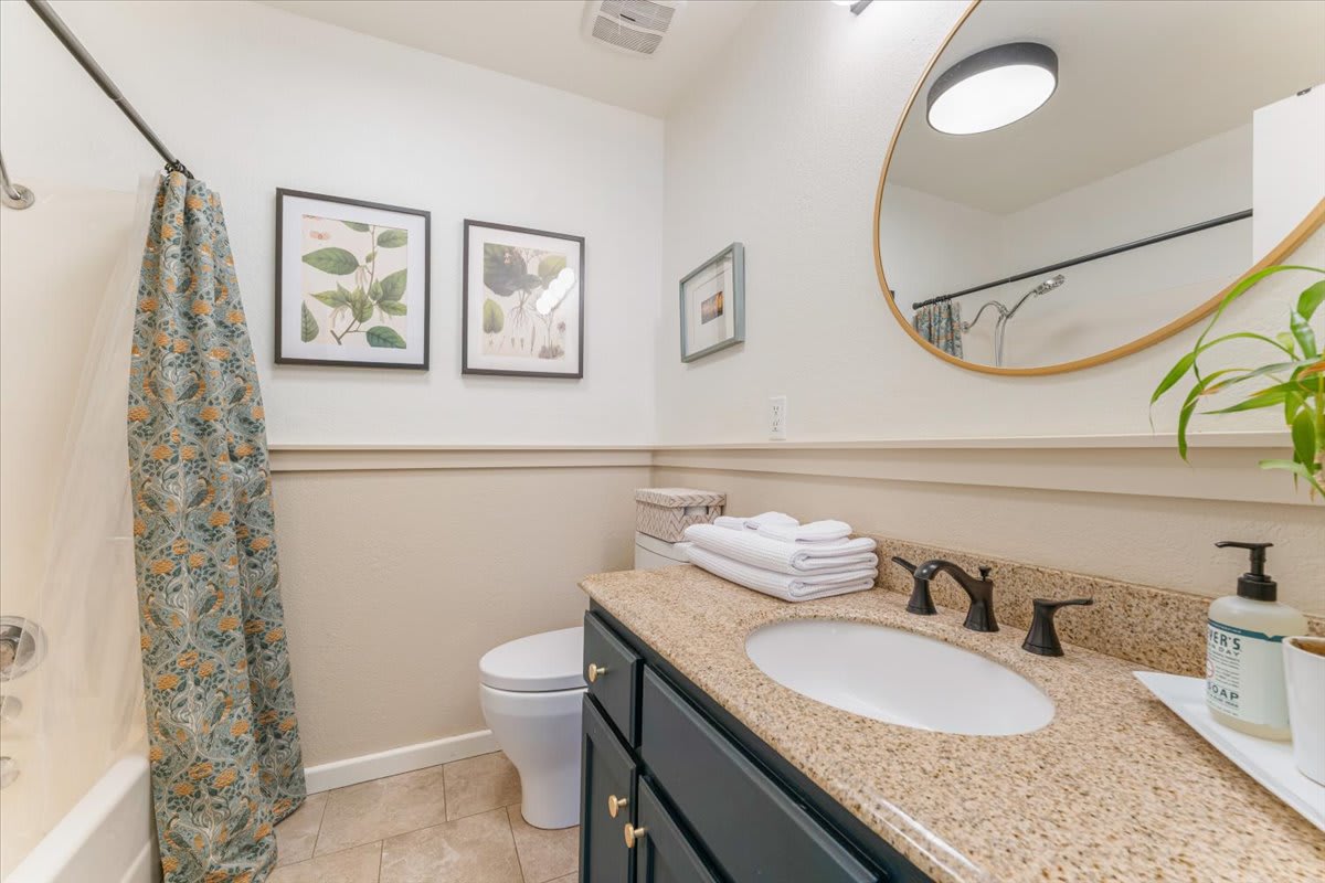 Bathroom in a Truckee vacation rental with beige tiles, floral decor, and granite countertop.
