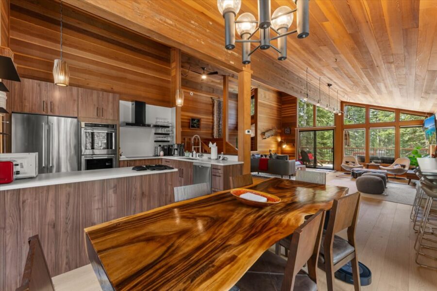 Modern open-plan kitchen and living area in a Carnelian Bay vacation rental with wood interiors and large windows.