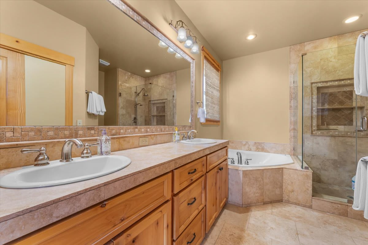 Luxurious bathroom in a Truckee vacation rental, featuring double sinks, a bathtub, and a spacious glass shower.