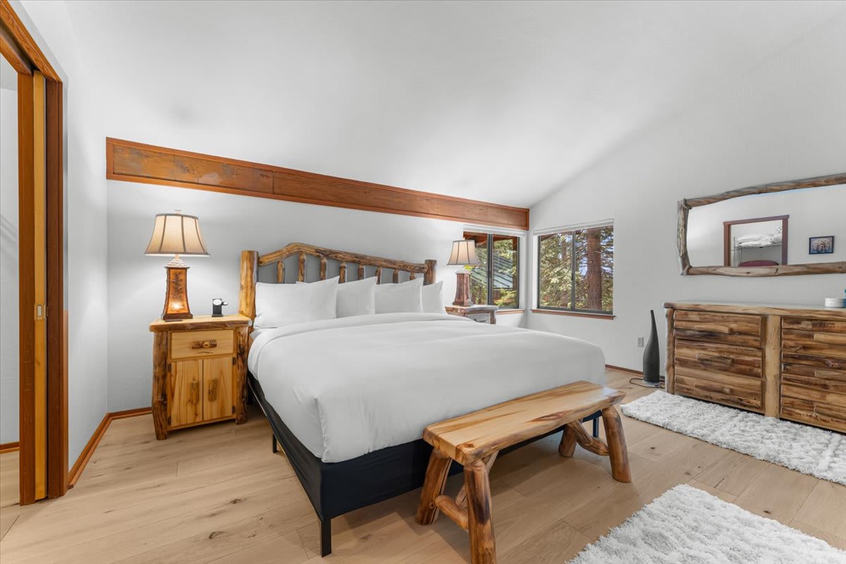 Cozy bedroom in a Carnelian Bay vacation rental with rustic wood furniture and large windows.