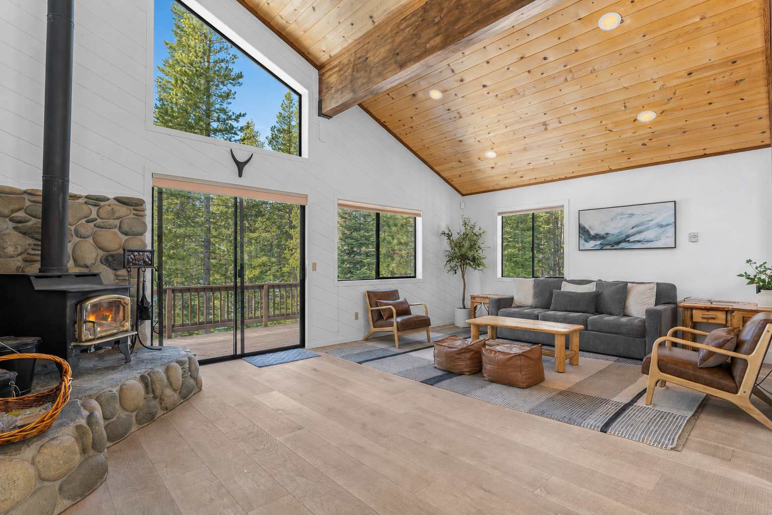 Spacious living room in a Truckee vacation rental with large windows, wooden ceiling, and cozy fireplace.