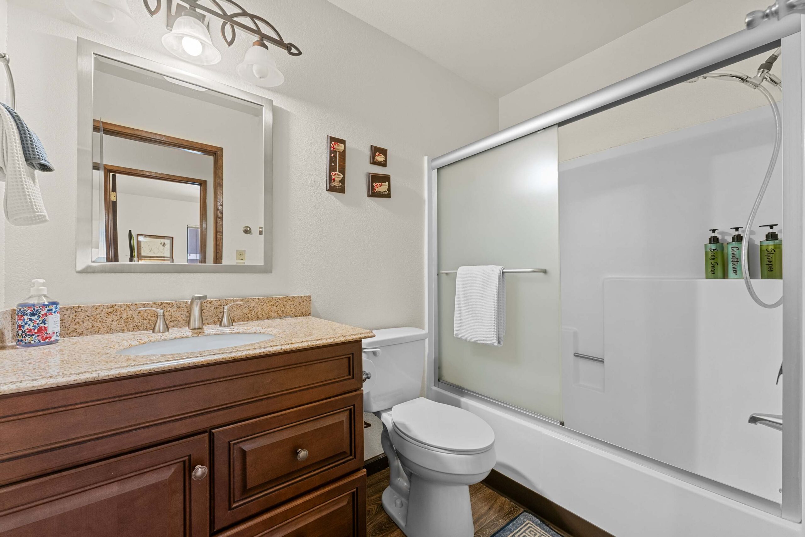 Bathroom in a Truckee vacation rental with granite countertop, mirror, shower, and wooden vanity.