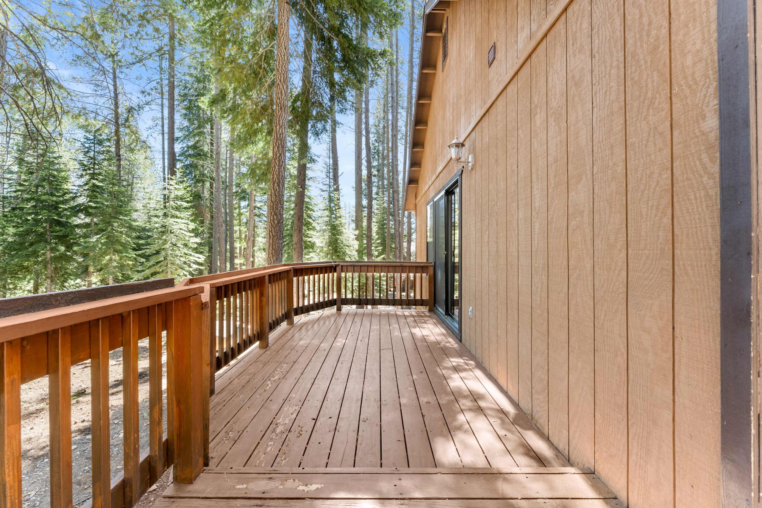 Wooden deck of a Truckee vacation rental surrounded by tall pine trees, offering a serene outdoor experience.