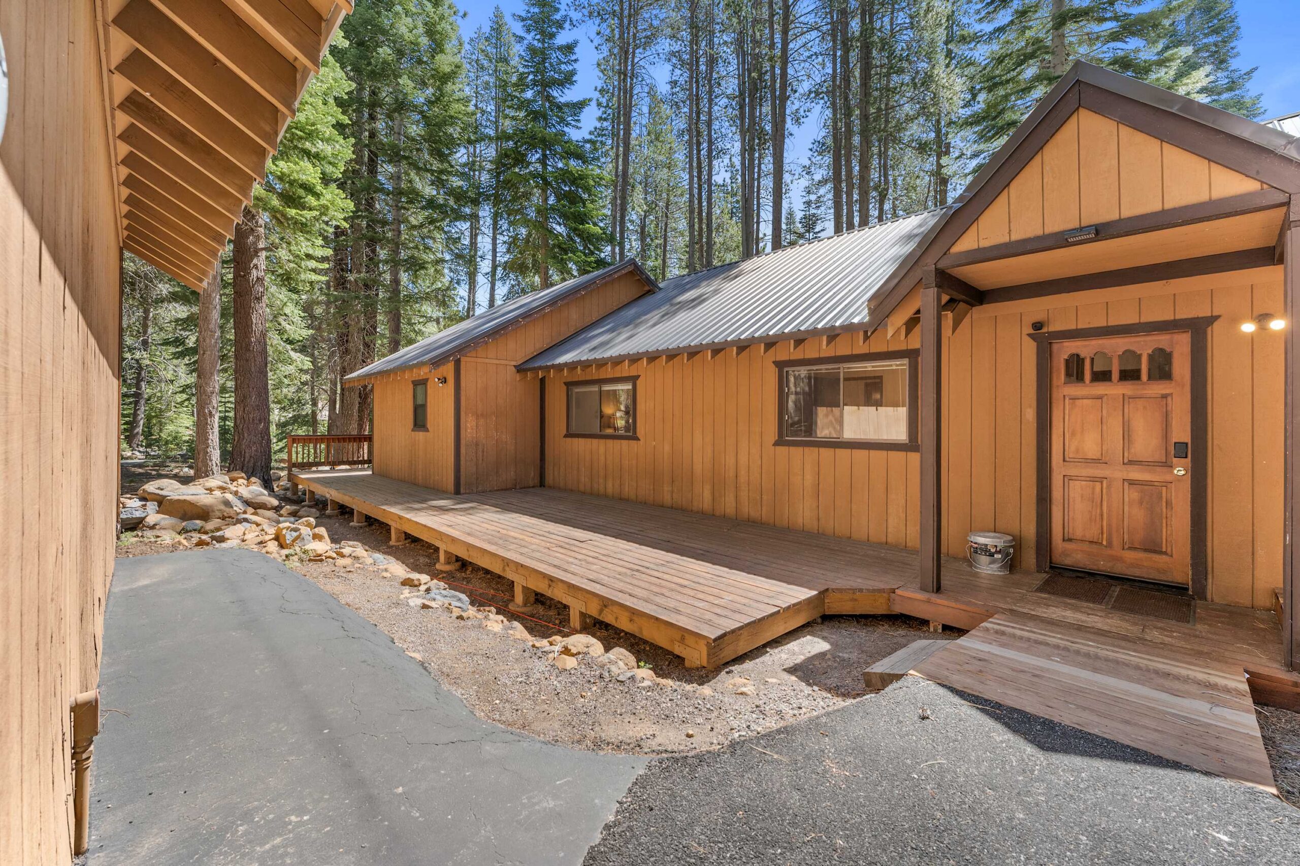 Wooden vacation rental cabin in Truckee, surrounded by tall pine trees, with a spacious deck and rustic charm.