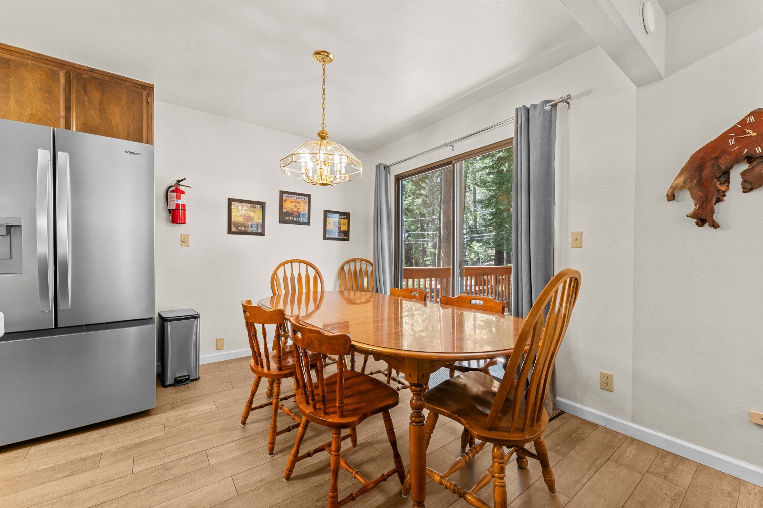 Dining area in a Truckee vacation rental, featuring a wooden table, chairs, and large windows with a forest view.