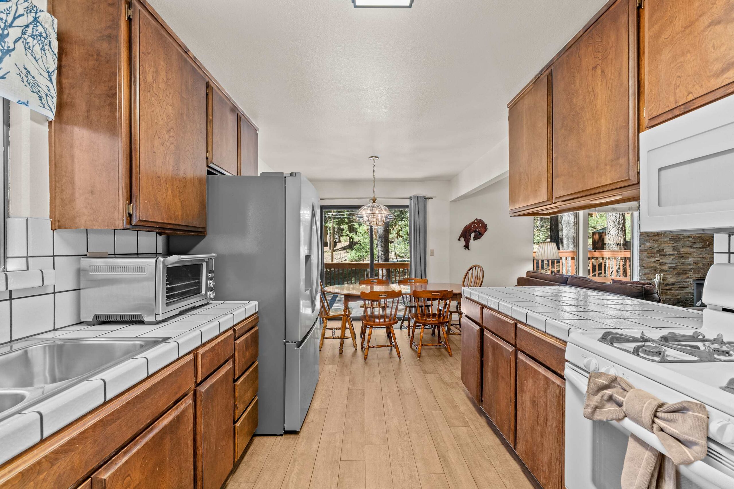 Cozy kitchen and dining area in a Truckee vacation rental with wood cabinets, tiled counters, and forest views.