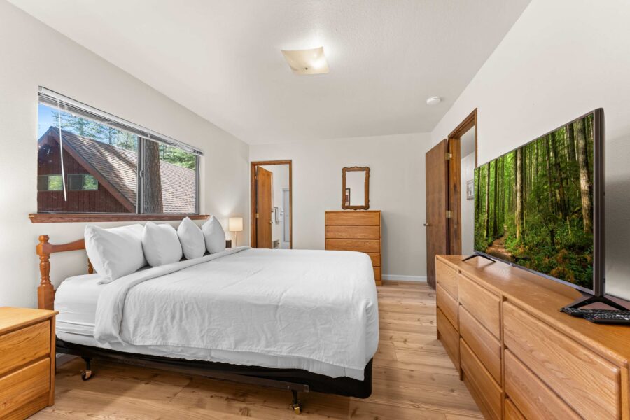 Bedroom in a Truckee vacation rental with a large bed, dresser, TV, and natural light through a window.