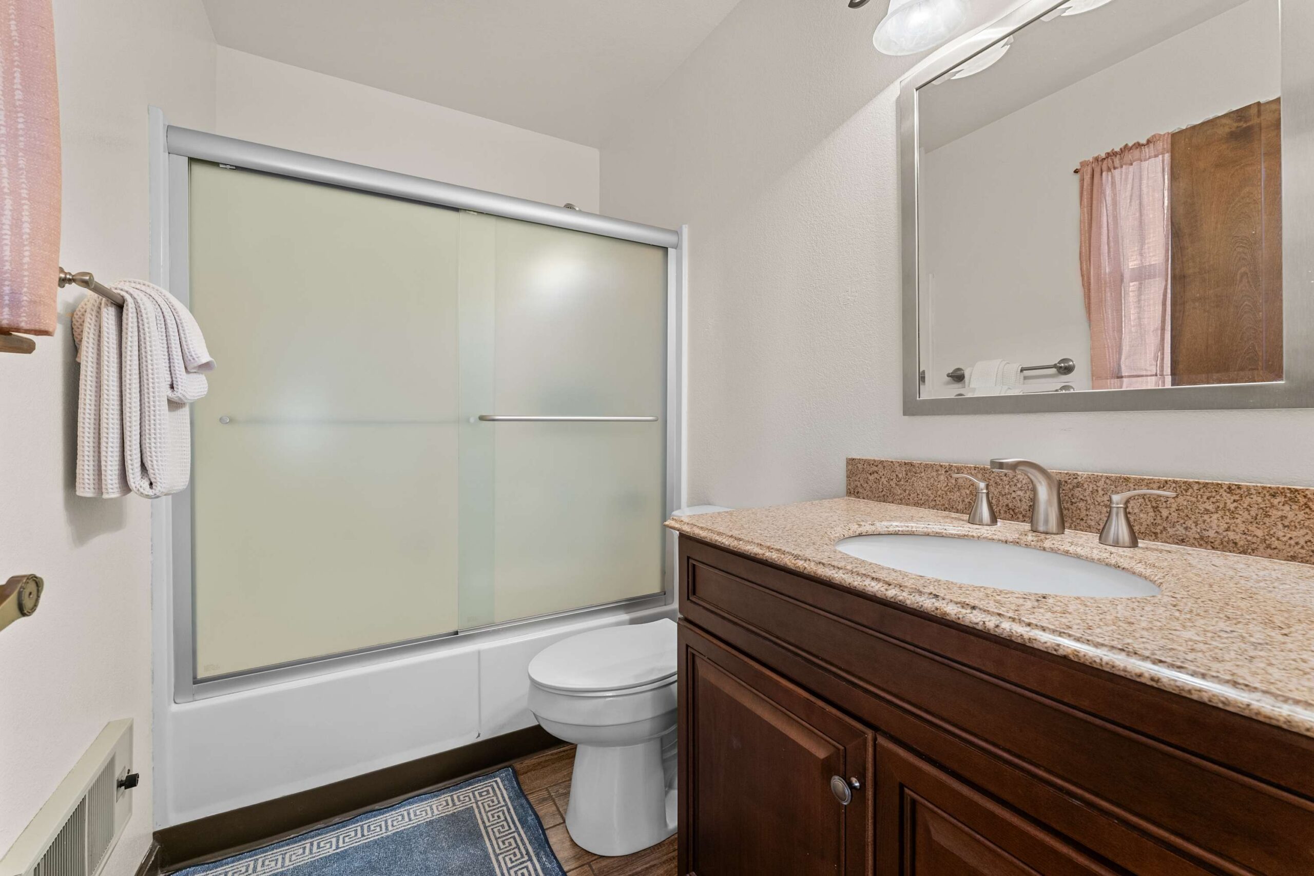 Bathroom in Truckee vacation rental with granite countertop, wooden vanity, and glass door shower.