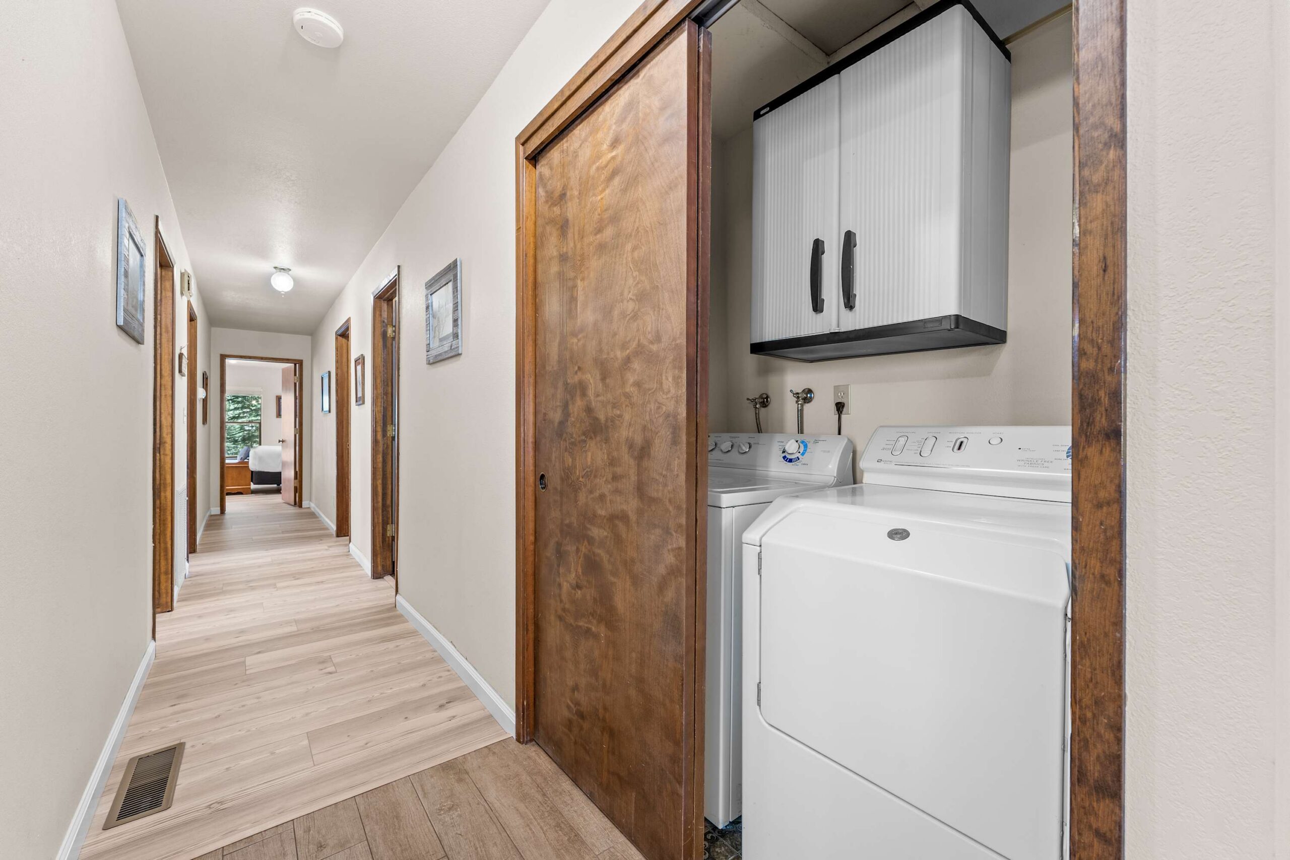 Hallway in Truckee vacation rental with wooden floor, laundry area, and bedroom view.