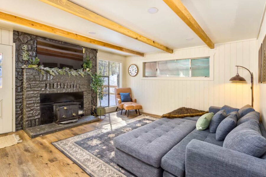 Cozy Kings Beach vacation rental living room with a large sofa, stone fireplace, and armchair by the window.
