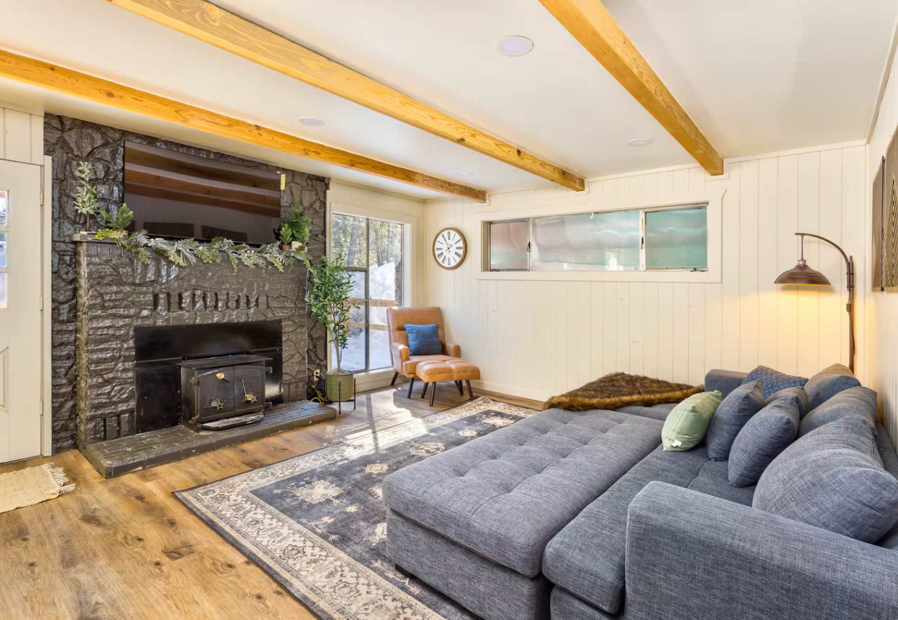 Cozy Kings Beach vacation rental living room with a large sofa, stone fireplace, and armchair by the window.