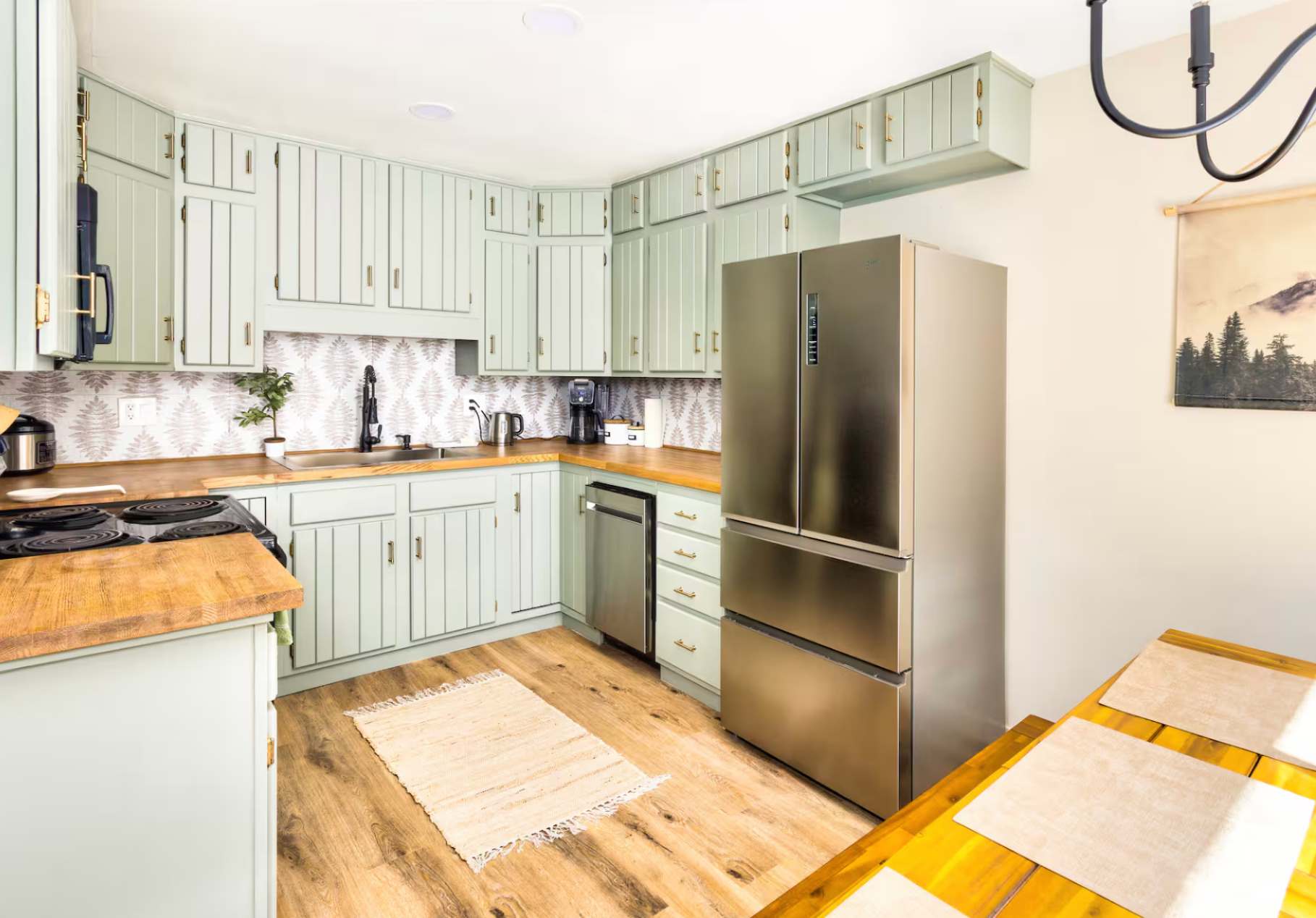 Bright kitchen in a Kings Beach vacation rental, featuring mint cabinets, wooden counters, and a stainless steel fridge.