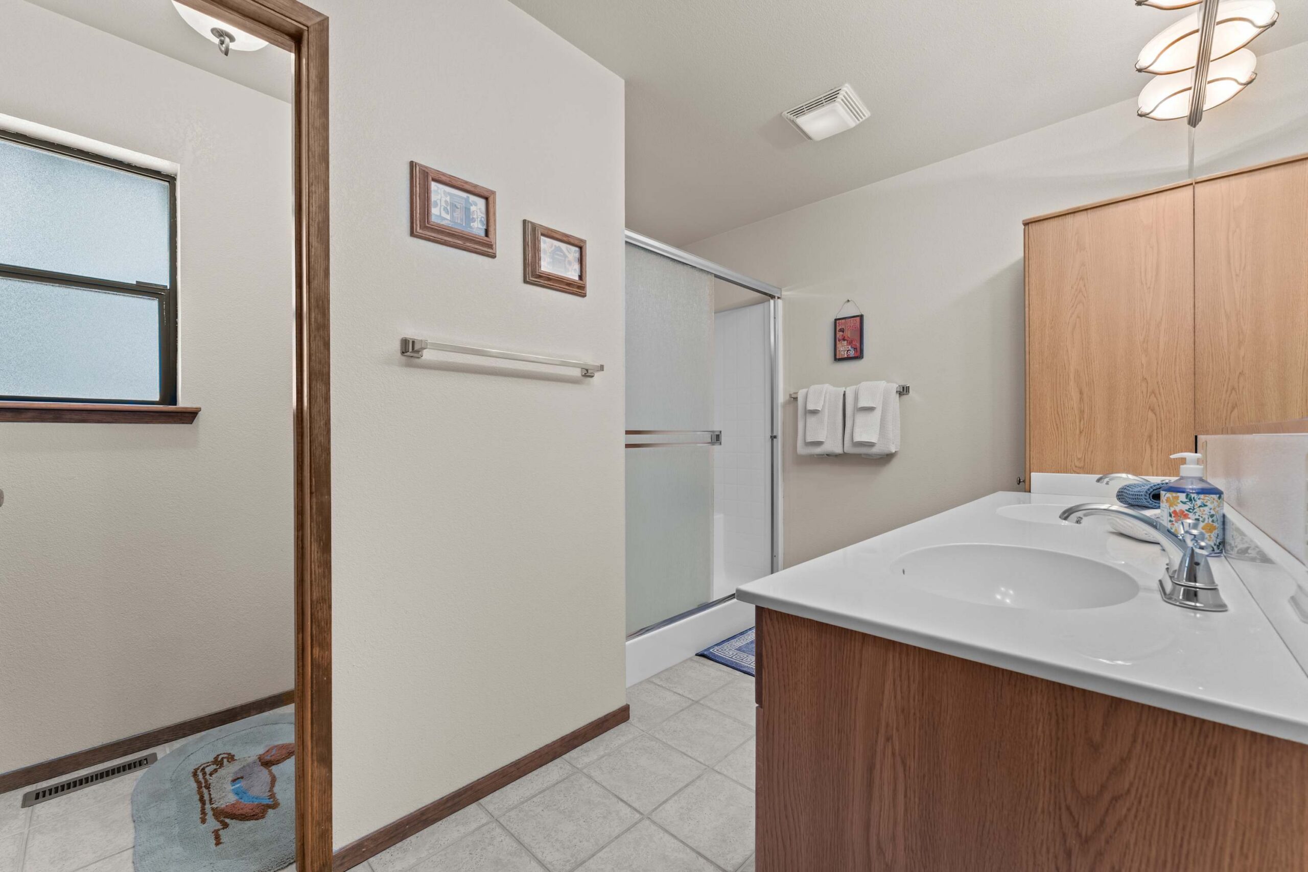 Bathroom in Truckee vacation rental with double sinks, wood accents, shower, towels, and framed wall art.