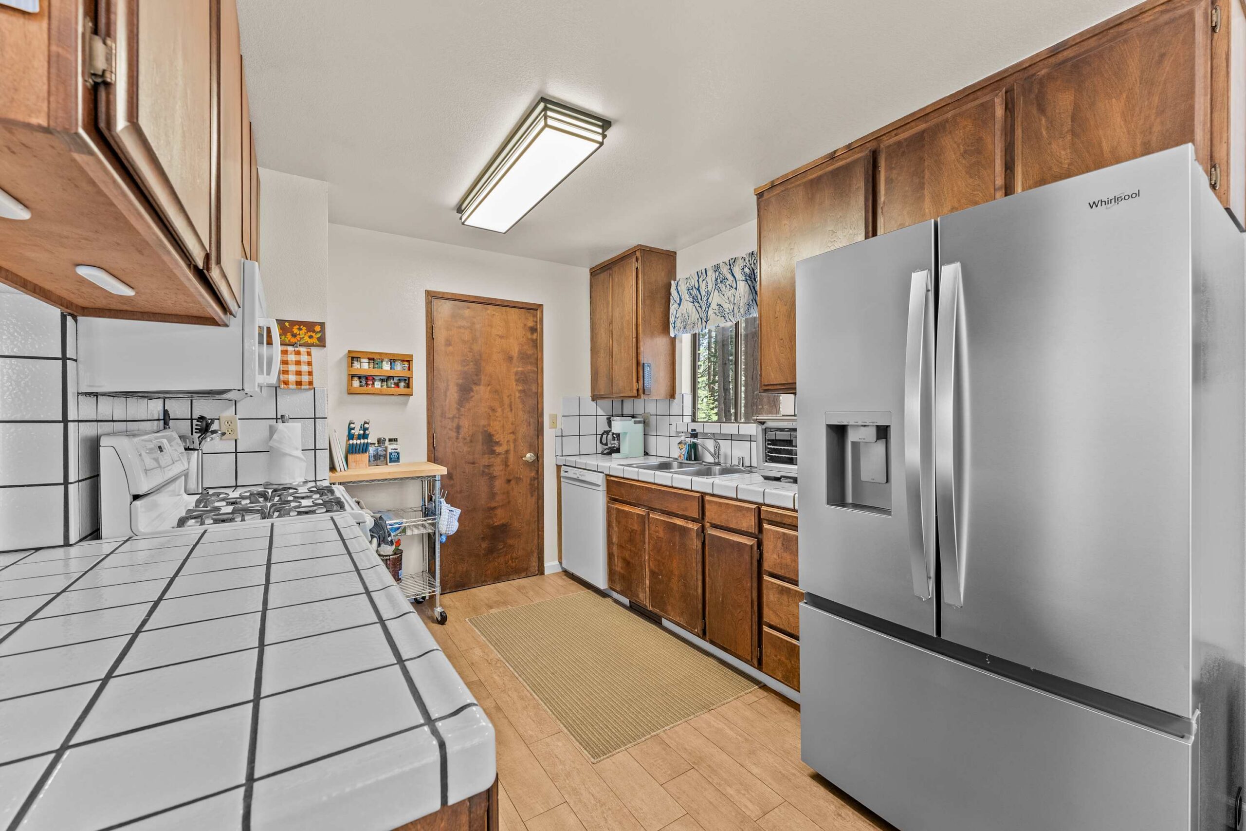 Modern kitchen in Truckee vacation rental with stainless steel fridge, wooden cabinets, and tiled countertops.
