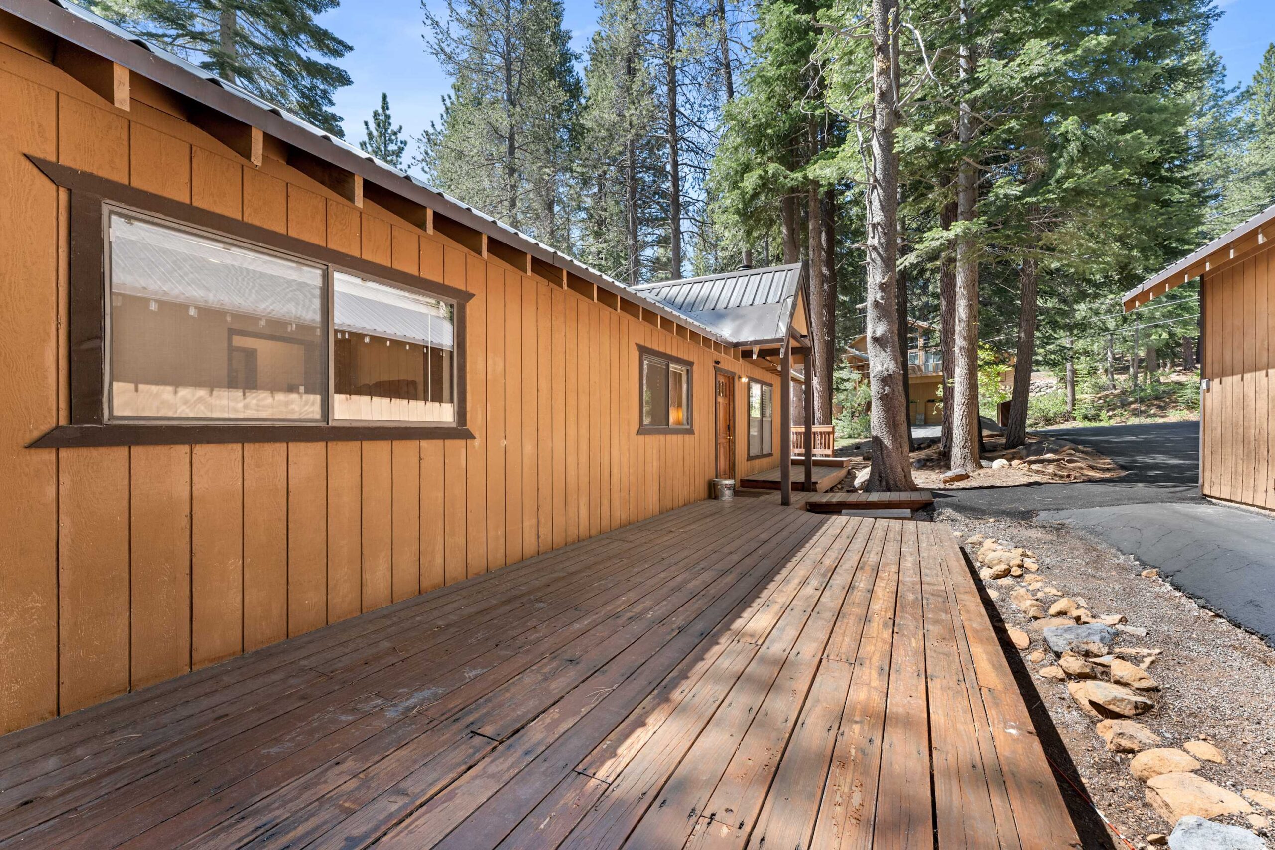 Truckee vacation rental: Rustic cabin exterior with wooden deck surrounded by tall pine trees.