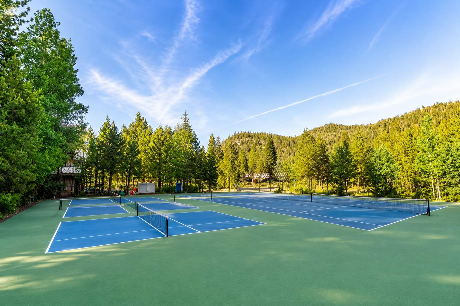 Tennis courts surrounded by trees in Olympic Valley, ideal for a vacation rental experience in nature.