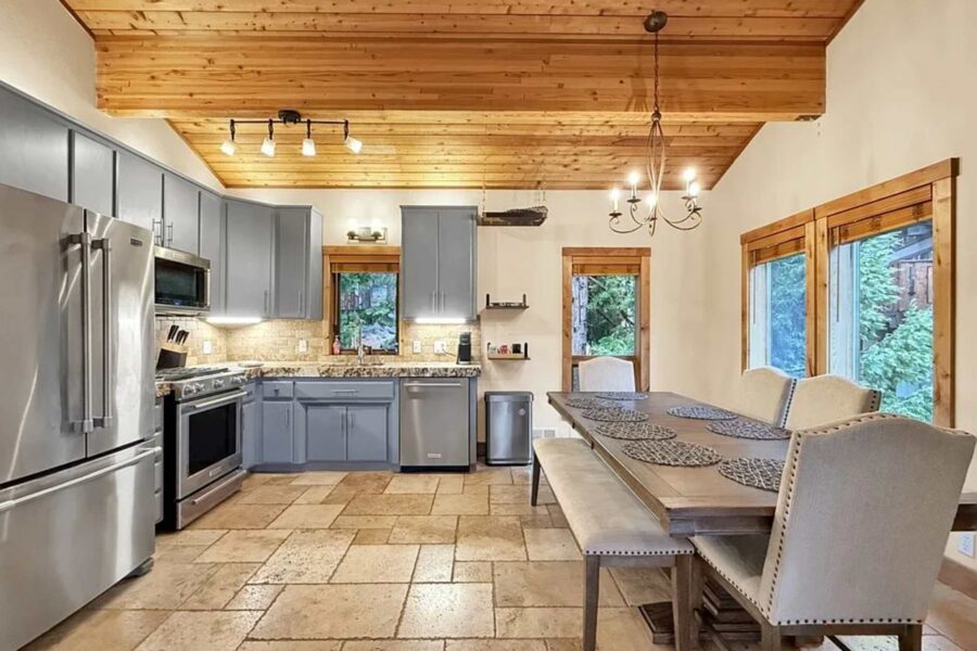 Rustic kitchen and dining area in an Incline Village vacation rental with wooden ceiling, modern appliances, and large windows.