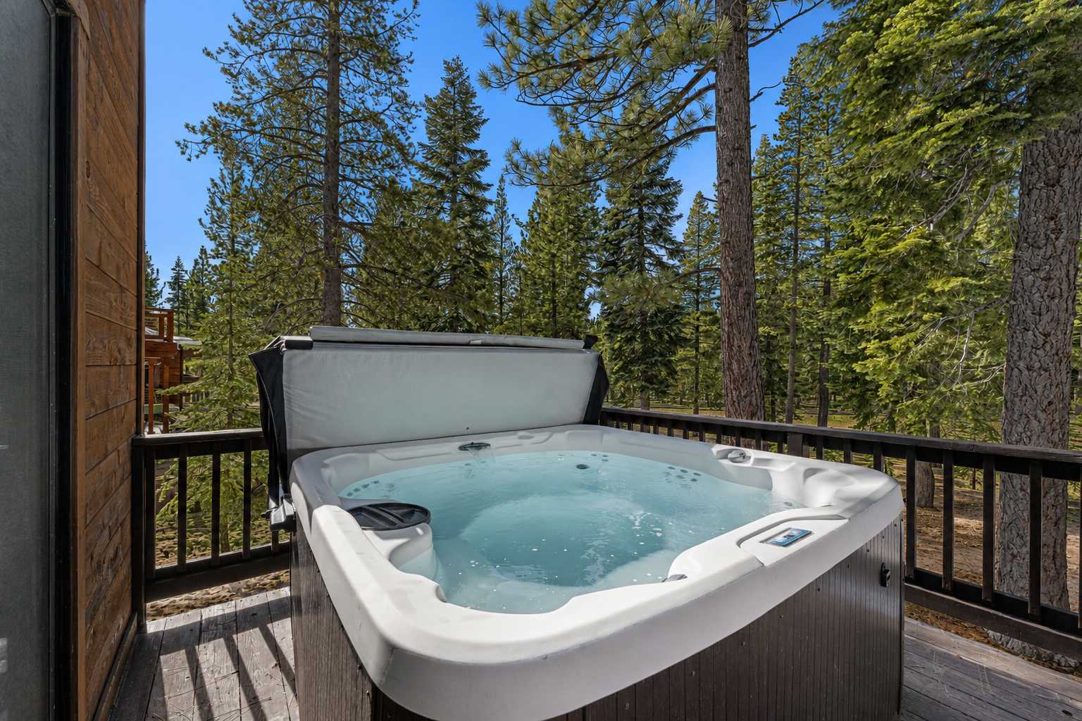 Hot tub on a deck surrounded by trees at a Truckee vacation rental, offering a serene forest view.