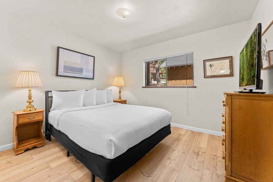 Cozy bedroom in a Truckee vacation rental with a comfy bed, wooden furniture, and artwork on the walls.
