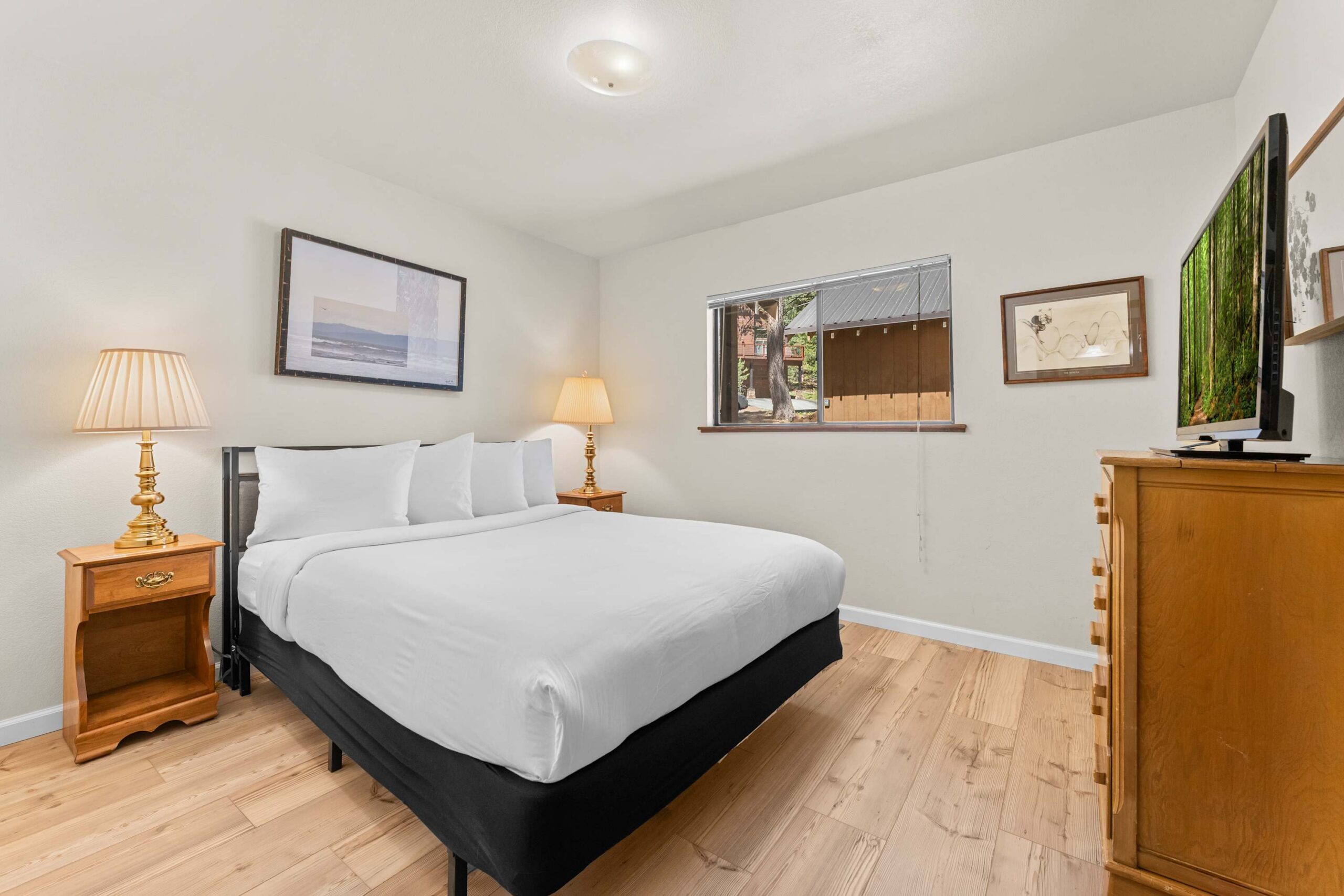 Cozy bedroom in a Truckee vacation rental with a comfy bed, wooden furniture, and artwork on the walls.